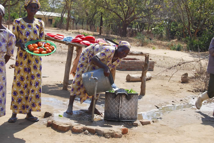 A Cook at Calvary Feeding Center prepares a meal of tomatoes, lettuce and Nsima (corn).