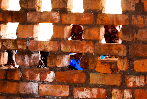 Orphans look through church windows which have no glass to stop deadly malarial mosquitos.
