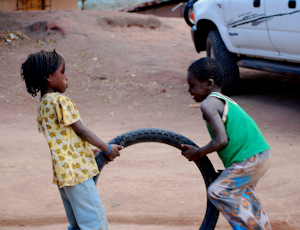 Malawi orphans play with a bicycle tire, a treasured toy.