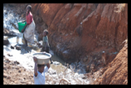 Women gather to collect water, clean clothes, etc. at a filthy river bottom